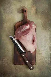 Raw pork knuckle, on a wooden chopping board