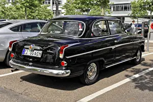 The rear view of a black classic car in a parking lot in sunny weather