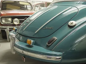 Rear view of a blue vintage car with chrome-plated bumper under a hall ceiling