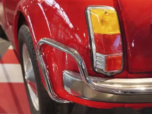 Rear view of a red classic car with shiny chrome bumper