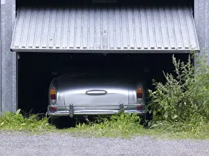 Rear view of a VW Karmann Ghia under a half-open garage door