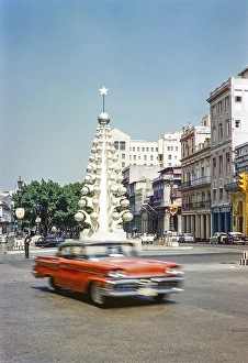 Red American Mercury car driving past the Christmas tree sculpture, Havana, Cuba, late 1950s or early 1960s Building, Central America
