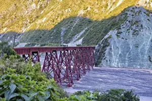 Red bridge over a dry riverbed in a mountainous landscape