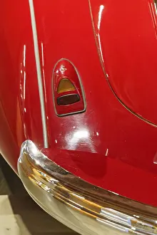 Part of a red classic car with chrome accents and shiny surface