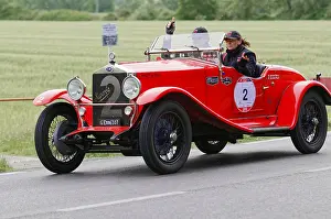 Red classic car with driver and co-driver on a country road during a rally