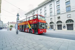 Red double-decker bus on a city street with historic buildings