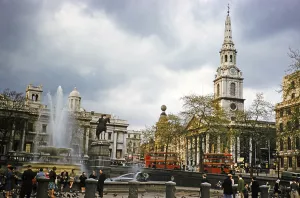 Red double-decker buses drive past the church of St Martin in the Fields, Trafalgar Square, London, England, UK 1962