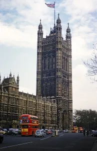 Red double-decker buses drive past the church of Westminster Abbey, London, England, UK 1962