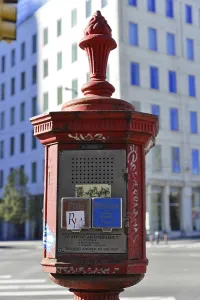 Red emergency call pillar in an urban environment with historical flair
