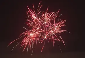 Red fireworks glow in vivid trails of light in the dark