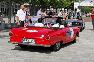 Red Ford convertible on a street with people during a classic car event