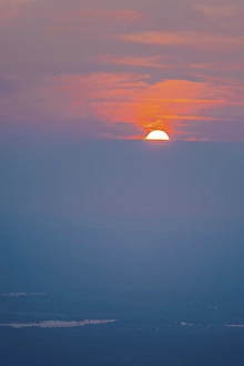 Category Mountain Landscapes Prints: Red glowing sun, sunset behind clouds on the horizon