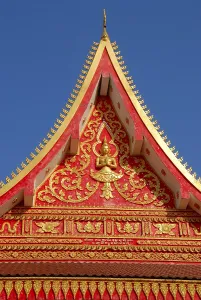 Red and golden decorated gable of a Buddhist temple Wat That Luang Vientiane Laos