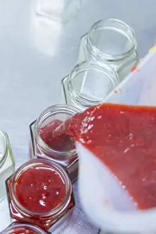 Red jam is filled into jars, fruity and fresh