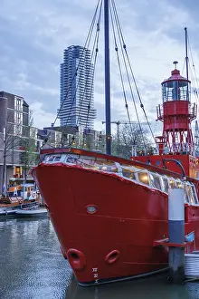 A red lighthouse ship in the water under modern high-rise buildings in the city