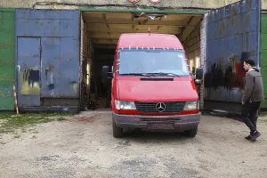 Red Mercedes van in front of a garage with a person nearby