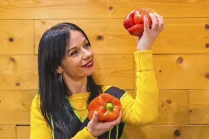 Red peppers in the hand of a brunette Caucasian fruit girl