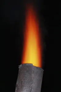 Red torch flame over the old metal chimney at night