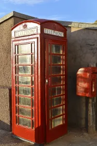 Red, traditional British telephone box next to a post box