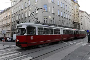Red tram travelling through an urban environment with historic buildings