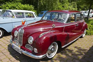 Red vintage car from the 50s in a car park in front of a forest
