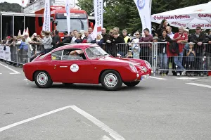 A red vintage car during a rally on the race track in front of spectators