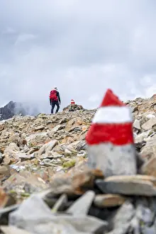 Red and white trail markings, hiker in the high mountains