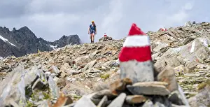 Red and white trail markings, hiker in the high mountains