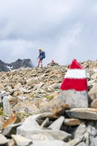 Red and white trail markings, hiker in the high mountains