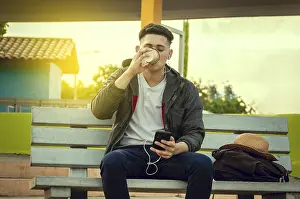 Relaxed attractive boy listening to music on a bench