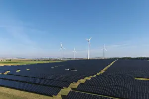 Renewable energy stations with solar panels and wind turbines in an open area