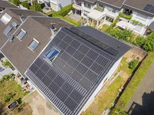 Residential roof with solar modules above a well-kept residential area