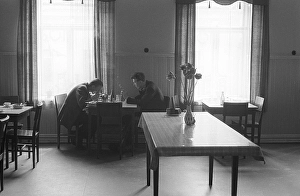 Restaurant 1954. Two men sit together at a simple piece of furniture table and chairs having a meal