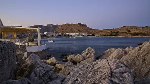 Restaurant Argo, Rock-framed view of a coastal town and sea at dusk