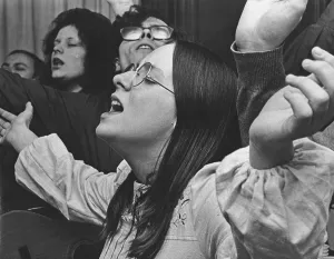 Revival meeting. Participants in a free church meeting sing and pray together visibly focused and in the moment