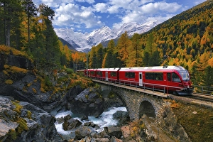 Rhaetian Railway RhB crossing a mountain stream over a stone bridge