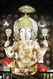 Richly decorated idol of Lord Ganesh kept in gaily decorated frame elephant headed god