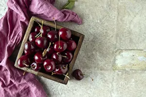 Ripe cherries lie in a wooden square box