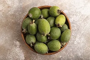 Ripe Feijoa in wooden bowl on brown concrete background