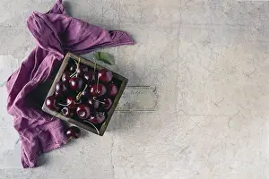 Ripe large cherries lie in a wooden square box