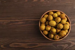 Ripe Longan in wooden bowl on brown wooden background