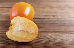 Ripe orange persimmon on brown wooden background