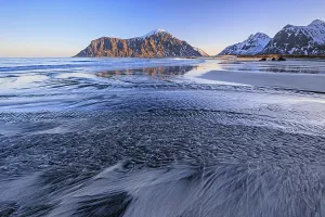 River course on the beach in front of snowy mountains