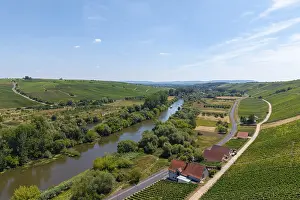 A river flowing through a landscape flanked by vineyards and a road