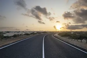 Road through a dune. Sunrise in the morning on a road with clouds in the sky