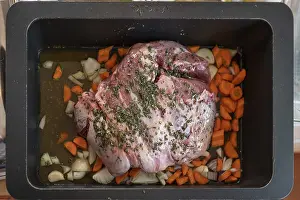 Roast lamb with herbs and vegetables in a casserole in front of roasting