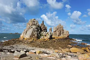 Rock formations on a sunny coast under a blue sky with clouds