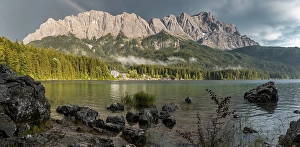 Rocks on the shore, Eibsee lake in front of Zugspitze massif with Zugspitze with rainbow