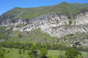 A rocky cliff with numerous caves carved into the rock face