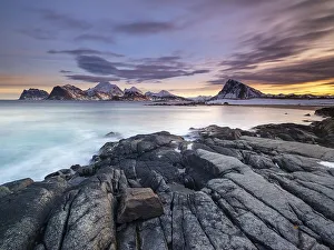 Rocky coast, snow-capped mountains in the background